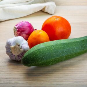 An image of zuchini, onion, garlic, and tomato. summer veggie tostada