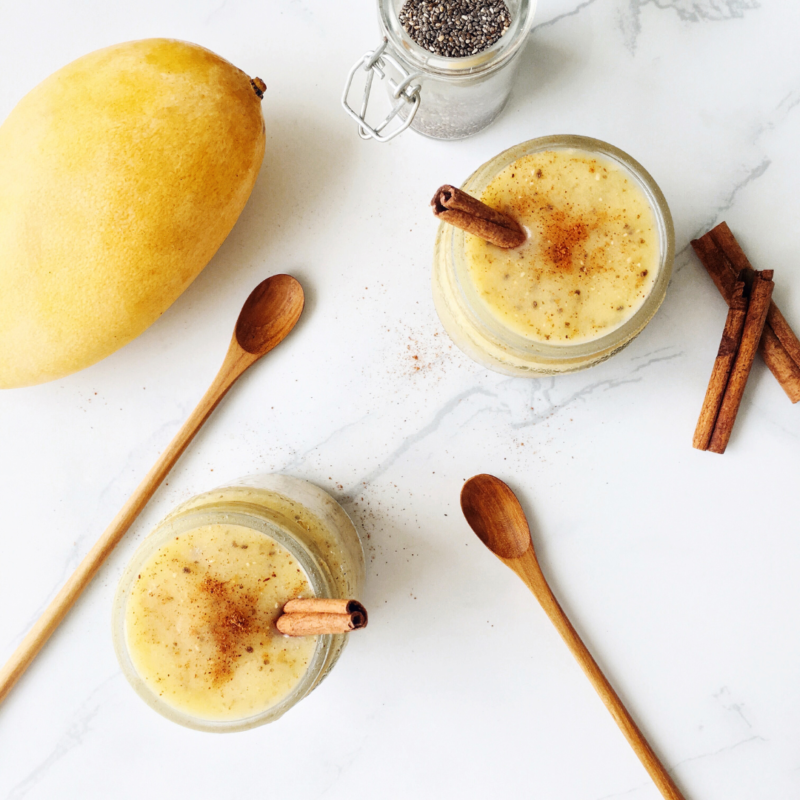 Image of whole mango and cut mango with wooden spoons, cinnamon sticks and chia seeds