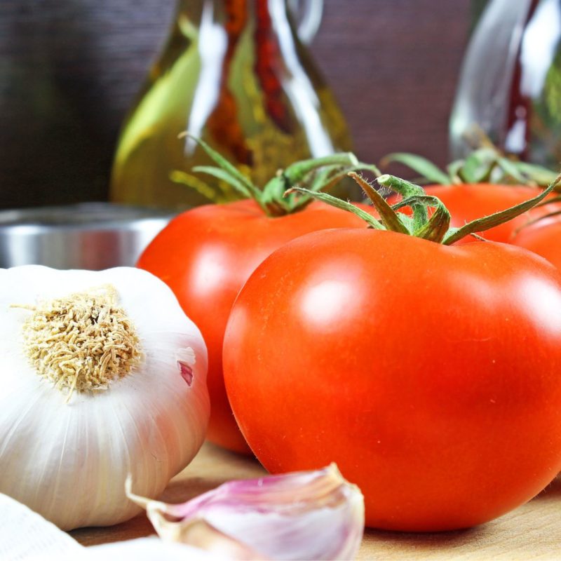 Closeup image of whole tomatoes, garlic and single garlic clove for healthy recipes nutritionist ppma