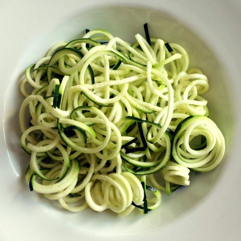 Image of zucchini noodles "zoodles" in white bowl, green to light yellow in color, curled for healthy recipe nutritionist PPMA