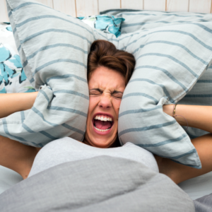 Image of person screaming and pressing pillow to the sides of their head insomnia sleep hygiene ppma