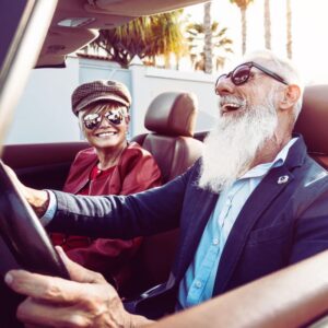 Image of older couple wearing sunglasses and laughing as they drive in convertible car. PPMA private physicians medical associates