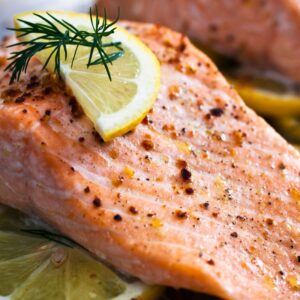 Image of baked salmon with lemon slice and sprig of parsley on top. source of omega-3 fatty acids. Romana Brennan MS RD. PPMA Private Physicians Medical Associates Concierge Medicine, Newport Beach, California