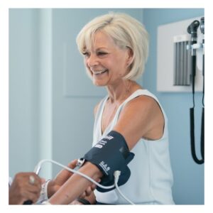 Image of a smiling, cheerful middle-aged woman having her blood pressure taken at the doctor's office. PPMA. private physicians medical associates