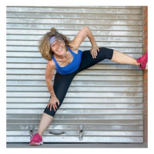 Image shows happy middle-aged woman in blue tank top, black workout pants, pink tennis shoes (sneakers) and blue headband on her curly hair, stretching in front of an aluminum pull-down door. quick tips for health. PPMA. private physicians medical associates
