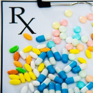 Image of an EX pad on clipboard with a variety of colorful pills and capsules spread out across the page. medication safety. PPMA. Private Physicians Medical Associates.
