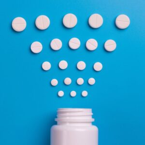 Image shows blue background with top third of a white pill bottle with white, round pills arranged above it. PPMA Private Physicians Medical Associates.