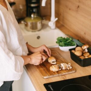 Image shows a person cutting mushrooms on a wooden cutting board with a basket of whole mushrooms nearby. Private Physicians Medical Associates. PPMA.