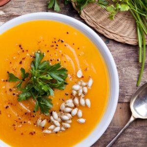 Image of a bowl of pumpkin soup with a green garnish and pumpkin seeds on top. PPMA. Private Physicians Medical Associates.
