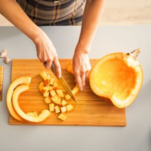Image shows the hands of a person cutting raw pumpkin into cubes. Pumpkin: A Superfood for All Seasons. PPMA. Private Physicians Medical Associates.