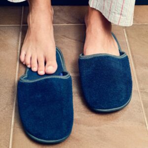 This is a picture of two blue slippers - one with the foot already inside and the other showing the foot about to enter the slipper.