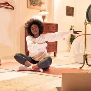 In this image, an African American woman is doing yoga before bedtime to enjoy the power of sleep.