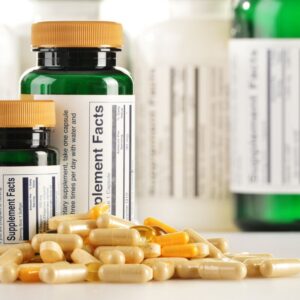 Supplement bottles with yellow capsules and tablets spread around them.