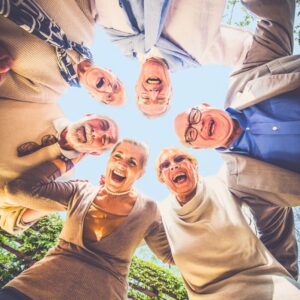 An image of six smiling seniors standing in a circle, looking down at the camera.