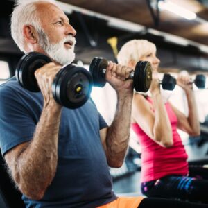 An image of a middle age or senior couple using hand weights to exercise at the gym.