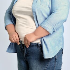 An image of an overweight or obese person trying button their jeans