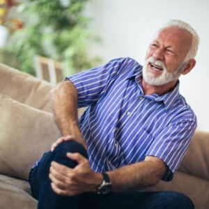 Senior man holding his knee, in pain.