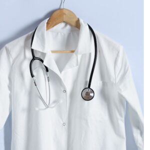 An image of a doctor's coat on a wooden hanger, with a stethoscope draped around the shoulders. Nurturing Patient-Physician Bonds
