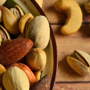 An image of part of a bowl of nuts with a few nuts on the table below.