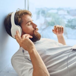 Image of a man reclining with eyes shut and headphones on, listening.