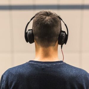 A man wearing headphones and a sweatshirt with his back to the camera