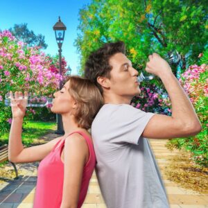 A couple drinking from their water bottles in the park.