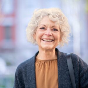 An image of a smiling senior woman with a blurry outside/building background. Understanding Sarcopenia: Silent Threat to Muscle Health