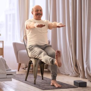 A middle-aged man or senior man performing stretching exercises from his chair.