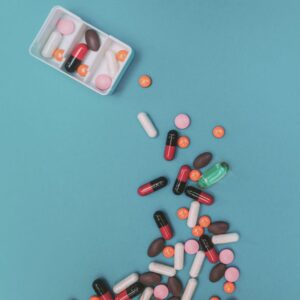 A graphic showing a pill dispenser with an array of pills below it, with a blue background.