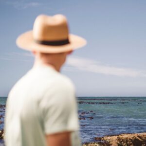 An image of a person at the shore wearing a hat to protect from the sun's harmful rays.