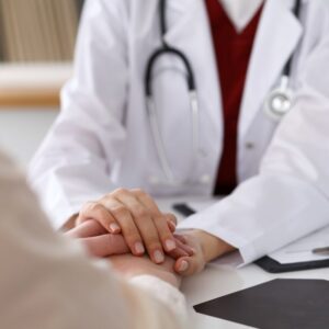 An image of a doctor's hands comforting those of a patient.