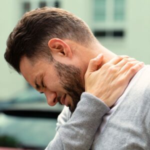 A profile image of a man wincing in pain as he touches his left shoulder.