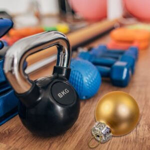 An image of workout equipment with a gold holiday ornament laying beside.