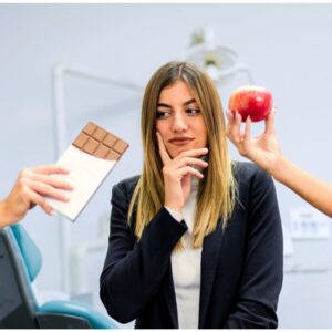 A young woman choosing between a chocolate bar and an apple, both being offered from people off-screen. Stick to New Year's Resolutions: Tips for a Healthier 2025.