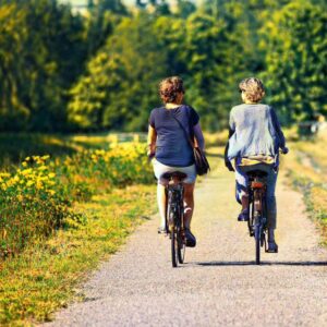 An image of adult women riding their bicycles in a park. Manage Stress for a Healthier Heart