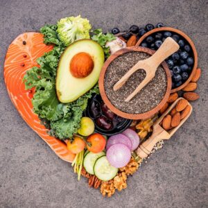 A heart-shaped image of heart-healthy foods, salmon, avocado, kale, broccoli, blueberries, almonds, and more. Eat for a Healthy Heart.