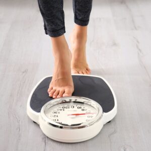 An image of a person stepping onto a scale in an effort to maintain a heart-healthy weight