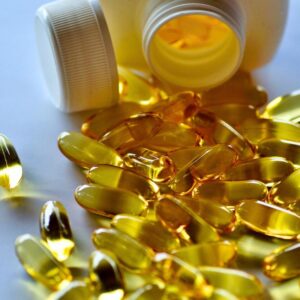 Amber vitamin supplements spilling out of bottle onto blue background. Fake Supplements: How to Identify and Avoid Them