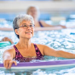 A middle-aged or senior woman participates in water aerobics.
