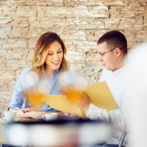 A vacationing couple looks at their menus in a restaurant, for healthy eating on the go during summer travel.