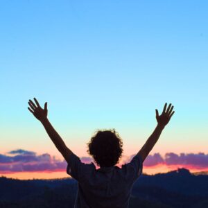 Person with arms in the air at sunrise